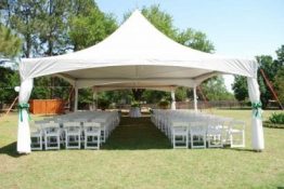 Chairs in rows under a white canopy for a wedding.